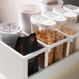 Kitchen cabinets with clear food containers in drawers.