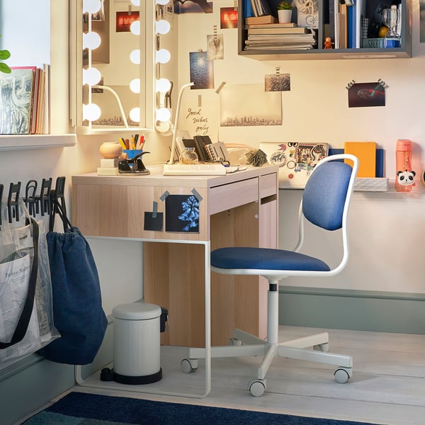 Desk area with MICKE light-wood desk, blue chair, various books, and decorations on shelves.