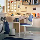 Desk area with MICKE light-wood desk, blue chair, various books, and decorations on shelves.