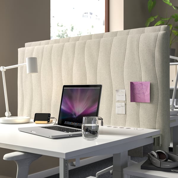Modern workspace with MITTZON acoustic screen. Cream-colored, sound-absorbing, tall desk divider. Laptop, water, lamp. Cozy, professional.