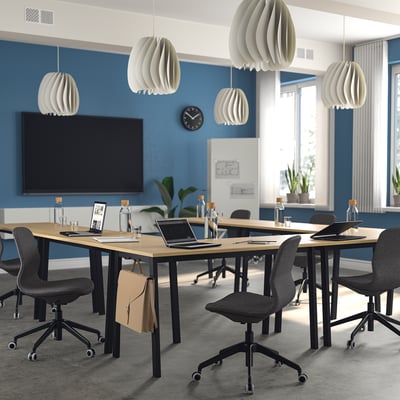 Modern conference room with MITTZON tables, grey chairs, blue walls, and a large screen.