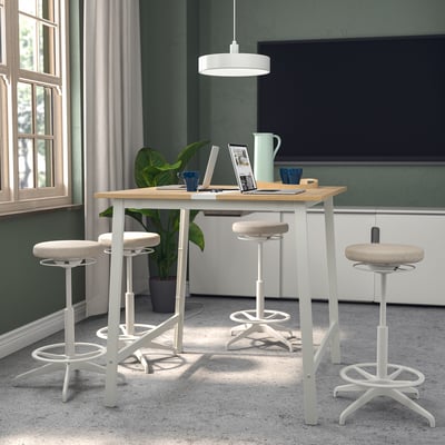 Modern conference table with 4 white stools, light wood top, metal legs, cable management, adjustable footrests, large window, tv, tableware.