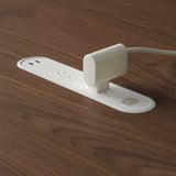 White table power outlet panel with usb ports on wooden table.