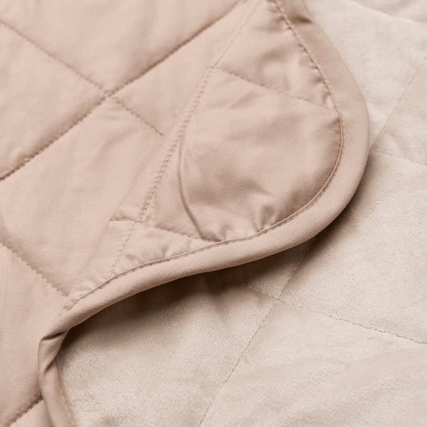 Close-up of luxurious beige bedspread, showcasing soft, quilted polyester velvet.