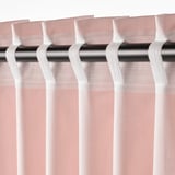 Close-up of sheer pink curtains with white tabs and hooks for hanging on rods, offering light filtration and privacy.