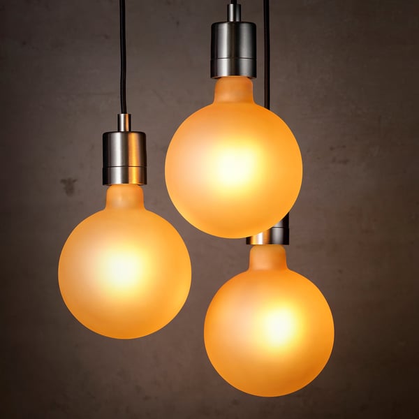 Three warm, brown glass globe lights hang from silver fixtures, emitting a cozy, soft glow.