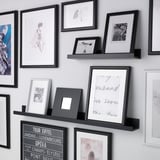Wall display shelves holding framed art and photos, with a groove to support smaller frames.