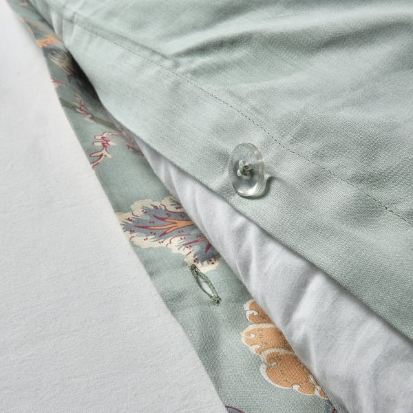 Close-up of light green, floral-patterned pillowcase fastener. Button-style closure for secure fit.