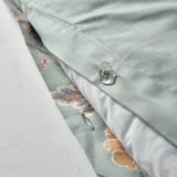 Close-up of light green, floral-patterned pillowcase fastener. Button-style closure for secure fit.