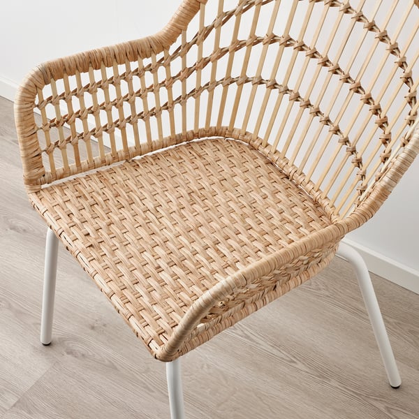 Wicker chair with bamboo back, elegant hand-woven design, white metal legs.