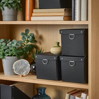 Wooden shelf with black storage boxes, small plant, and decorative items.
