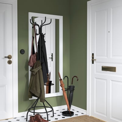 Small black NIPÅSEN umbrella stand holds 2 umbrellas beside white doors.