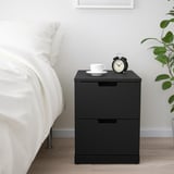 Bedside table with drawers and alarm clock. Simple and modern design, ideal for bedroom storage.