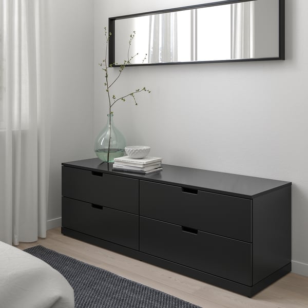 Black NORDLI chest with mirror, green vase, and books.
