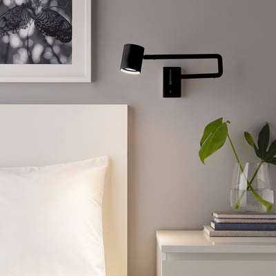 Bedside wall lamp NYMÅNE with adjustable light direction, dimmable for various lighting needs, providing focused light suitable for reading.