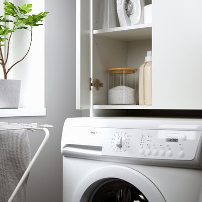 A white NYSJÖN cabinet, featuring a sleek design with two doors, perfect for storing items above a washing machine.