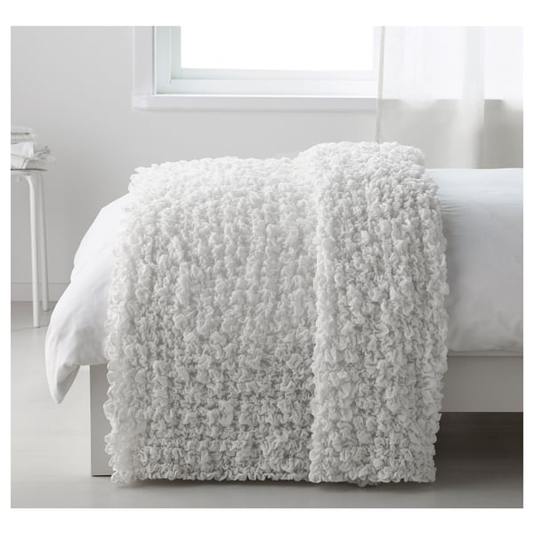 A white OFELIA bed blanket, textured and cozy, draped over a bed, suitable for 180 cm beds.
