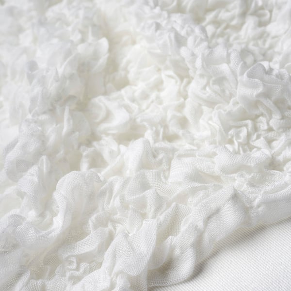 Soft white ruffled fabric, close-up view. Texture appears smooth and delicate, likely made from recycled polyester and acrylic.
