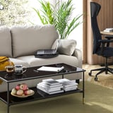 Modern living space with gray sofa, black laptop tray, green rug, and wooden floor.