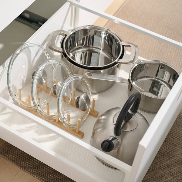 Kitchen drawer organizer with bamboo lid holders and stainless pots.