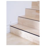 Wooden stairs with black anti-slip strips on each step for safety.