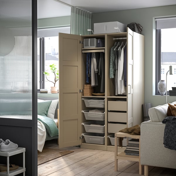 Modern bedroom with beige PAX wardrobe featuring clothes, drawers, and mesh baskets. Soft closing doors and gray curtains.