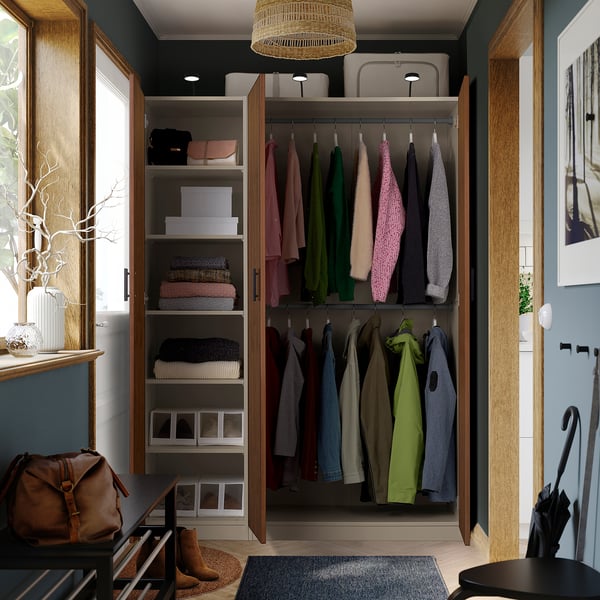 Open wardrobe with clothes, shelves, and storage boxes. Hanging garments visible, organized by color.