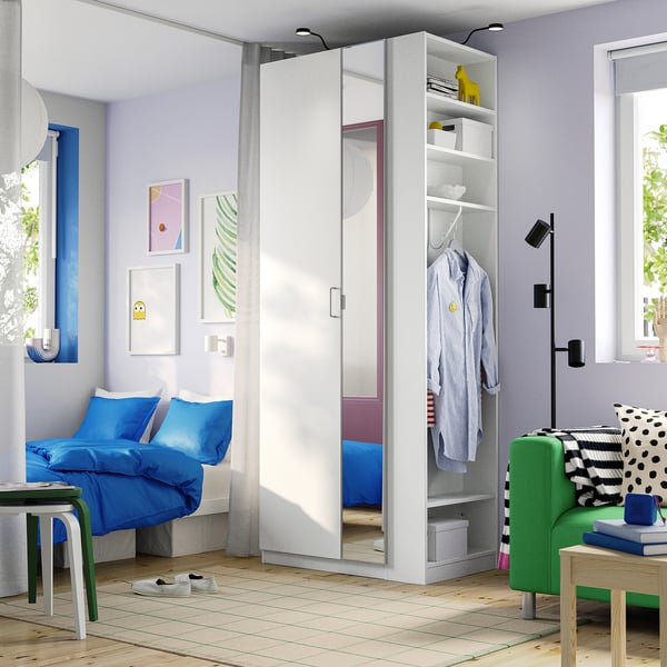 Modern bedroom with white PAX wardrobe, mirror doors, blue bed, green sofa, wooden floor.