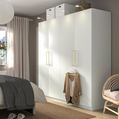 Modern white PAX wardrobe, tall & slim, fits a cozy bedroom. Gold handles, half hanging, half shelved.