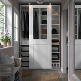 Open PAX wardrobe with clothes, glass doors, neat organization in a cozy room.