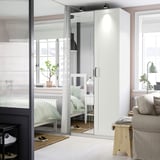 Minimalist bedroom with large lit mirror wardrobe between windows.