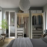Modern bedroom with open wardrobe, displaying clothes and storage solutions. Soft lighting highlights organized space.