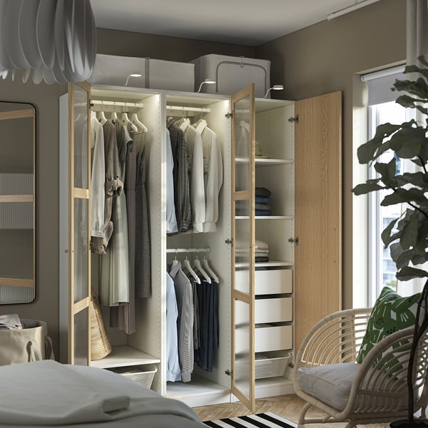 Modern bedroom with open wardrobe showcasing clothes, shelves, and drawers. Integrated lighting illuminates organized storage solutions.