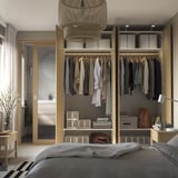 Bedroom with open wardrobe displaying clothes, shelves, and storage boxes. Light fixture hangs above, reflecting modern organization.