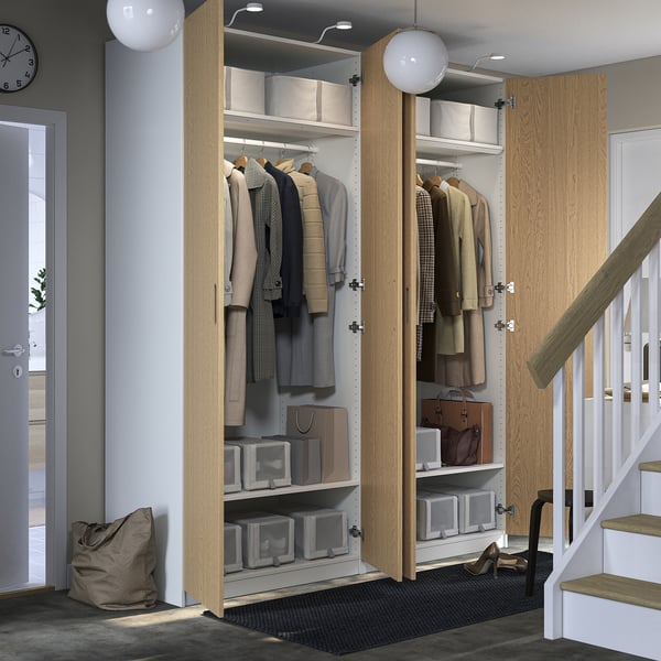 Modern closet with open doors, clothes and boxes. Near staircase, clock on wall.