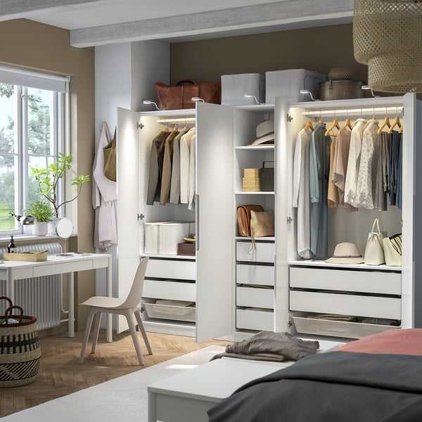 Modern bedroom with open PAX wardrobe displaying clothes, shelves, and storage boxes.