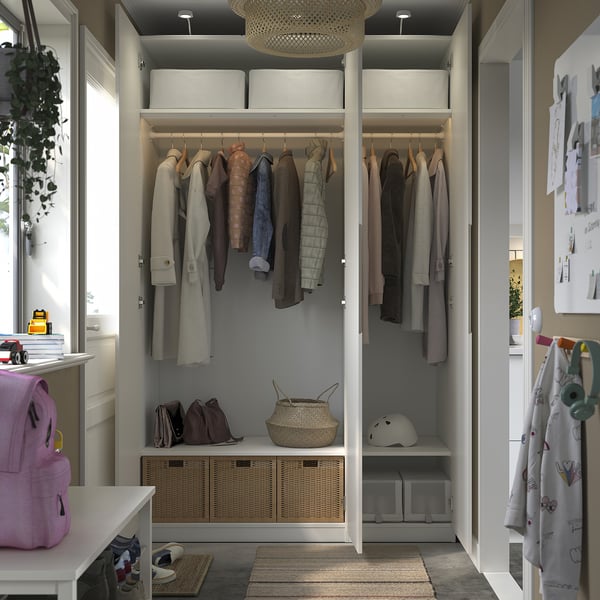 Modern closet with clothes, helmets, bags, and open shelves, lit by a chandelier.