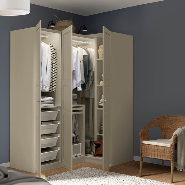 A modern beige wardrobe with open doors reveals neatly organized clothes, shelves, and white laundry baskets. It stands against a dark blue wall.