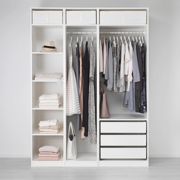 A minimalist wardrobe, PAX, featuring shelves with stacked clothes and hanging garments, drawers, and adjustable feet for floor compensation.