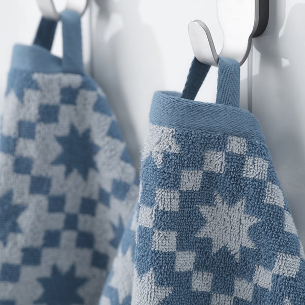 Two blue and white patterned towels hang neatly on hooks, showcasing their soft, absorbent material and festive design.