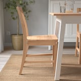 A wooden chair with a slanted backrest situated by a dining table, showcasing its comfortable seat designed for extended use.
