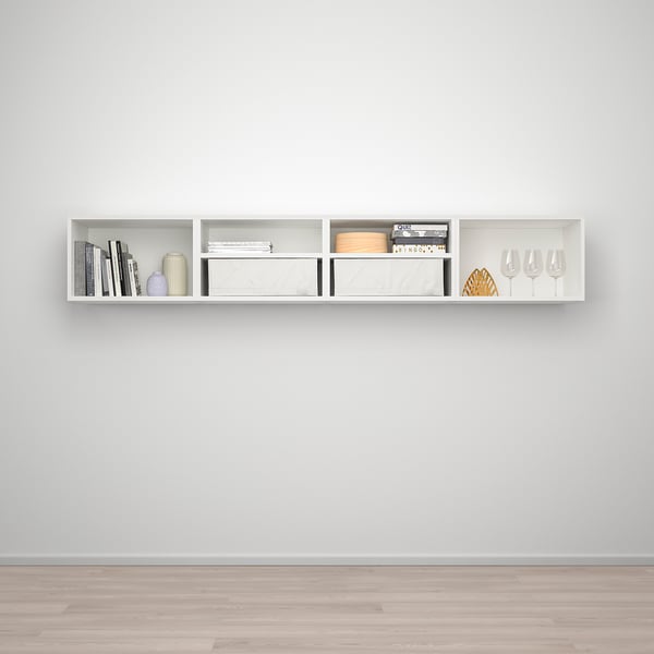 A white, modern wall-mounted shelf, PLATSA, holds books, vases, and glasses neatly on a grey wall.