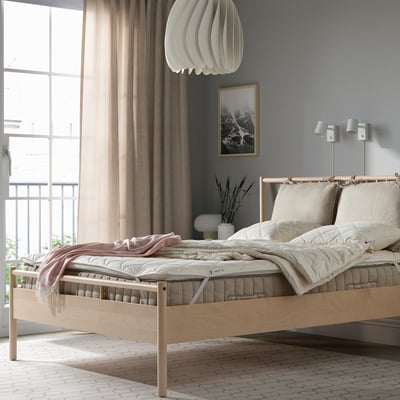 Bedroom with RÅDHUSVIN protector on light bed, large window, and lamp.
