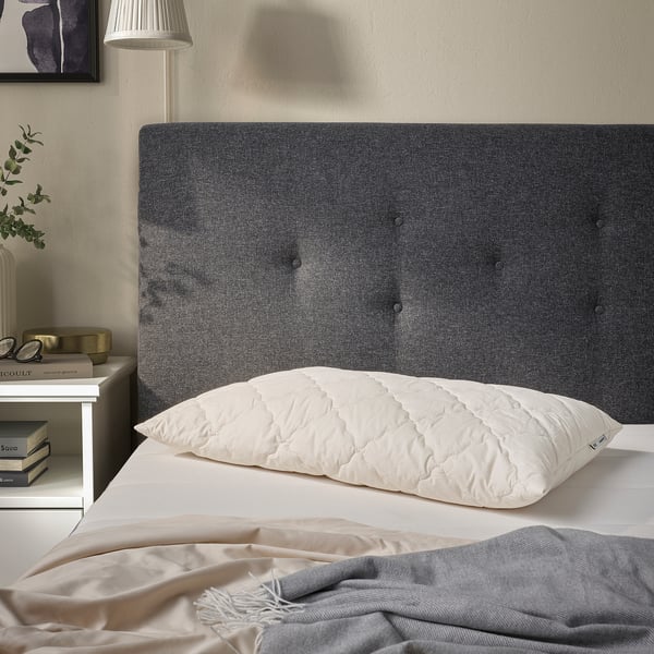 White cotton-wool pillow on bed, quilted, smaller than book.