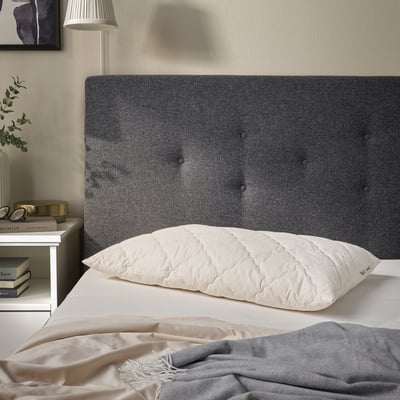 White cotton-wool pillow on bed, quilted, smaller than book.