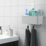 A bathroom organizer basket with hooks hangs on a tiled wall, holding bottles, dispensers, and towels with strong suction cups.