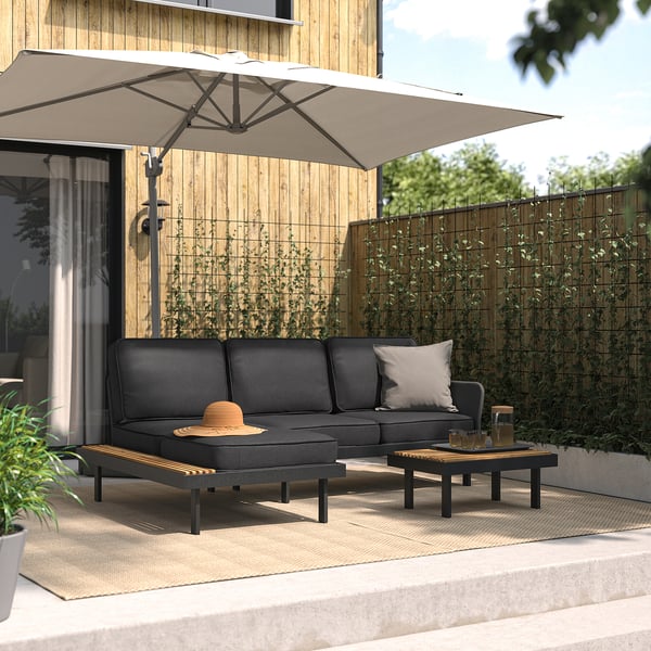 Modern patio set: black sofa, side table, and chaise under beige umbrella on deck.