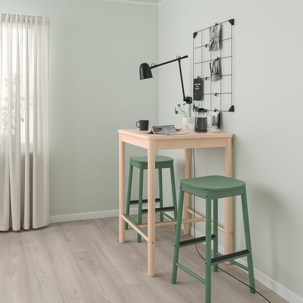 Small modern bar set with light wood table and green stools, perfect for small spaces.