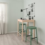 Small modern bar set with light wood table and green stools, perfect for small spaces.