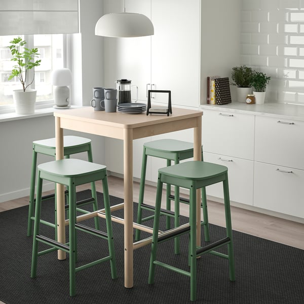 Small modern dining set with green bar stools and light wood table.